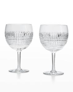 two clear goblets sitting next to each other on a white surface with no one in it