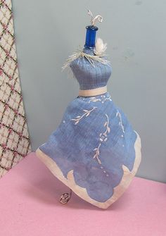 a blue dress with white flowers on it is sitting on top of a pink table