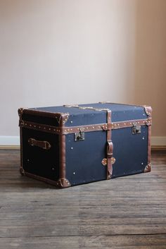 an old trunk is sitting on the floor in front of a wall and wooden floors