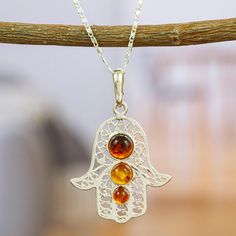 The Hamsa is an ancient amulet intended to protect against the evil eye. The Del Toro family handcrafts this 925 sterling silver pendant necklace embellished with amber stones that symbolize courage and self-confidence. This necklace will accompany you in your daily life as a protection and as a symbol of your courage and hardworking spirit. Spiritual Sterling Silver Charm Necklace With Gemstone, Spiritual Amber Gemstone Necklace, Baltic Amber Gemstone Necklaces, Traditional Sterling Silver Healing Necklaces, Spiritual Sterling Silver Hallmarked Necklace, Spiritual Hallmarked Sterling Silver Necklaces, Sterling Silver Pendant Charm Necklace For Healing, Spiritual Citrine Amber Necklace, Traditional Sterling Silver Nickel Free Necklace