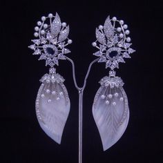 Add a touch of sophistication to your ensemble with our Blue Centerpiece earrings. Adorned with a lustrous silver pearl, these white stone earrings are the perfect accessory for any occasion. Elevate your style and make a statement today. Our CZ Jewelry Sets are the most difficult ones to make. It takes over 80 hours of Design work to design each of these handcrafted Masterpieces. Handcrafted in India by the finest Diamond Jewelry Craftsmen from West Bengal. Diamond-Like Brilliance: Enhanced with diamond CZ accents, the stones sparkle with brilliance and add a touch of glamour to the set. Versatile Elegance: Suitable for bridal wear, formal events, or any occasion where a touch of class is desired, this set promises to elevate any look with its timeless beauty. Impeccable Craftsmanship: Me Exquisite White Diamond Earrings For Evening, White Diamond Crystal Drop Earrings, Formal White Cubic Zirconia Chandelier Earrings, White Cubic Zirconia Chandelier Earrings For Formal Events, White Cubic Zirconia Chandelier Earrings For Formal Occasions, Formal White Crystal Earrings With Cubic Zirconia, Formal White Cubic Zirconia Crystal Earrings, Luxury White Crystal Earrings, White Diamond Chandelier Earrings For Pierced Ears