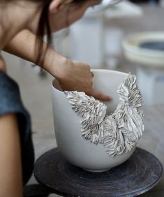 a woman is holding onto a white bowl with some sort of decoration on top of it