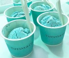 four cups filled with blue ice cream sitting on top of a white countertop next to each other