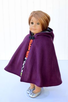 a doll wearing a purple cape and shoes