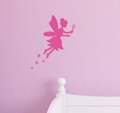 a pink fairy wall sticker on the side of a bed in a girls'bedroom