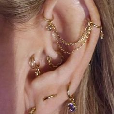 a close up of a person's ear with gold chains and piercings on it