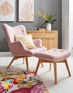 a pink chair and footstool in front of a wall with paintings on it