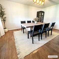 a dining room table with black chairs and a white rug on top of the floor