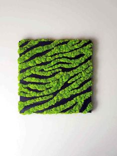 a piece of art made out of grass with black and green stripes on the surface