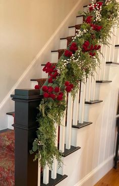 a set of stairs decorated with red roses and greenery for the christmas holiday season