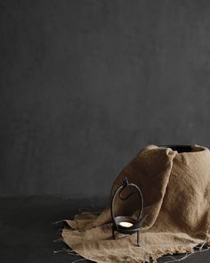 a brown cloth with a candle in it and a black vase on the table next to it