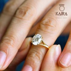 a woman's hand with a diamond ring on top of her finger and the other hand holding an engagement ring