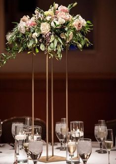 the centerpiece is surrounded by wine glasses and flowers in gold vases, along with candles