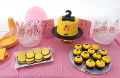 a table topped with lots of yellow cupcakes and cake covered in frosting