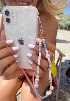 a woman is holding up her phone case with beads and charms attached to the cover