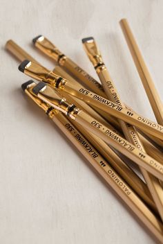 several gold colored pencils with writing on them