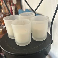 four white candles sitting on top of a black table