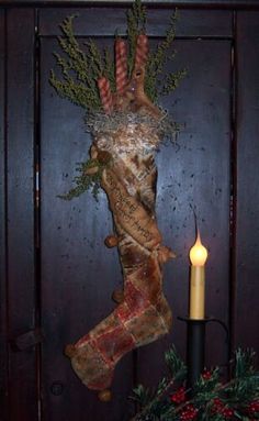 a candle is lit next to a fake christmas stocking hanging on a door frame