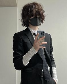 a person in a suit and mask taking a selfie with a cell phone camera