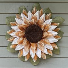 an orange and white sunflower is hanging on the side of a house's wall