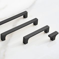 three black handles on a white counter top