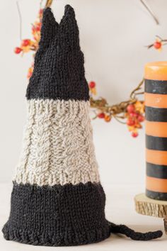 a knitted black and white hat sitting on top of a table next to a candle