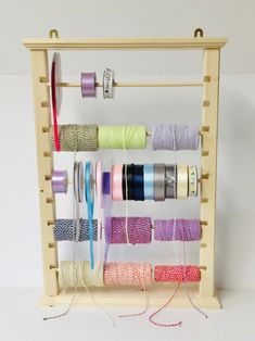 several spools of thread are hanging on a wooden rack