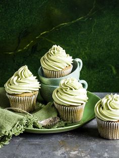 three cupcakes with frosting on a green plate