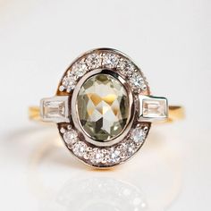 Reminiscent of art deco, this stunning ring by Carrie Elizabeth features a glowing green amethyst surrounded by shimmering cubic zirconia. Shop more vintage inspired rings at Local Eclectic. Art Deco Diamond Ring With Gemstone, Art Deco Multi-stone Diamond Ring, Art Deco Oval Diamond Ring With Accent Stones, Classic Diamond Multi-stone Amethyst Ring, Green Amethyst Ring With Center Stone For Wedding, Wedding Amethyst Ring With Green Center Stone, Green Amethyst Ring With Accent Stones Fine Jewelry, Fine Jewelry Green Amethyst Ring With Accent Stones, Elegant Green Amethyst Ring With Accent Stones