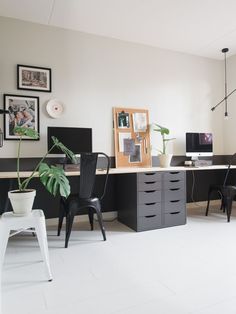 an office with two desks, chairs and pictures on the wall