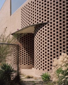 a building made out of bricks with plants in the foreground