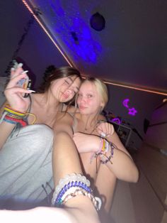 two young women sitting next to each other in a room with lights on the ceiling