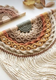 two crocheted rugs sitting on top of a table next to autumn leaves