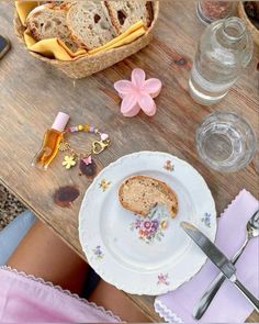 there is a plate with bread on it next to some glasses and flowers in the background