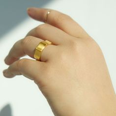 a woman's hand with a gold ring on top of her finger, against a white background