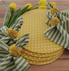 yellow and green napkins with flowers on them sitting on top of a wooden table