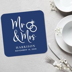 a blue square coaster with the words mr and mrs on it next to white dishes