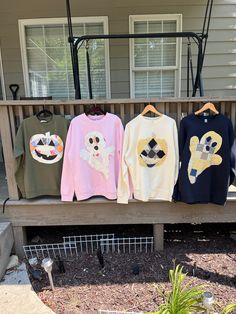 four sweaters are hanging on a bench in front of a house