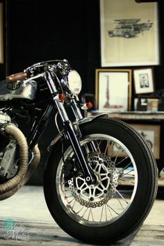 a black and white photo of a motorcycle parked in front of a table with pictures on it