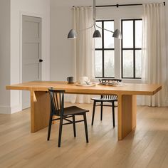 a dining room table with two chairs next to it and a window in the background