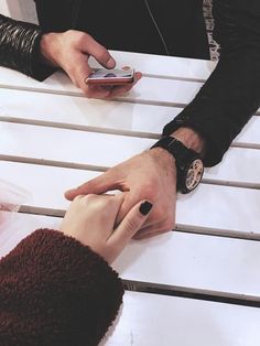 two people sitting at a table with their hands on each other's wrists