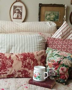 a coffee mug sitting on top of a bed next to pillows and other decorative items