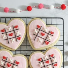 four decorated heart shaped cookies on a cooling rack