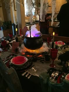 a table is set with red and white plates, silverware, and black candle holders