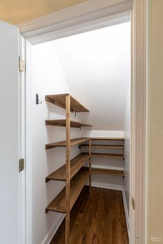 an empty walk in closet with shelving and wooden shelves on either side of the door