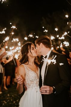 a newly married couple kissing while holding sparklers