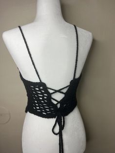 a white mannequin wearing a black crochet top with an attached tie