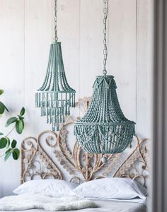 two chandeliers hanging from the ceiling over a bed