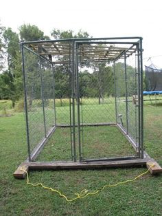 a dog kennel in the middle of a grassy field with a yellow rope attached to it