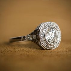 A rare and beautiful engagement ring. Circa 1920. The platinum engagement ring features a very lively 1.55 carat Old European cut diamond and is adorned with openwork filigree along the gallery and under-gallery. Old diamonds adorn the shoulders of the shank. Included to the center diamond, is a halo of diamonds around the center for an additional 0.36 carats. The ring is made from handcrafted platinum, from the Art Deco era and includes fine engravings. ✦ ENGAGEMENT RING SPECIFICATIONS: Center 1920 Engagement Ring, Estate Diamond Jewelry, Antique Engagement Ring, Antique Wedding Rings, Wedding Rings Halo, Antique Engagement, Deco Engagement Ring, Wedding Rings Unique, Wedding Rings Vintage